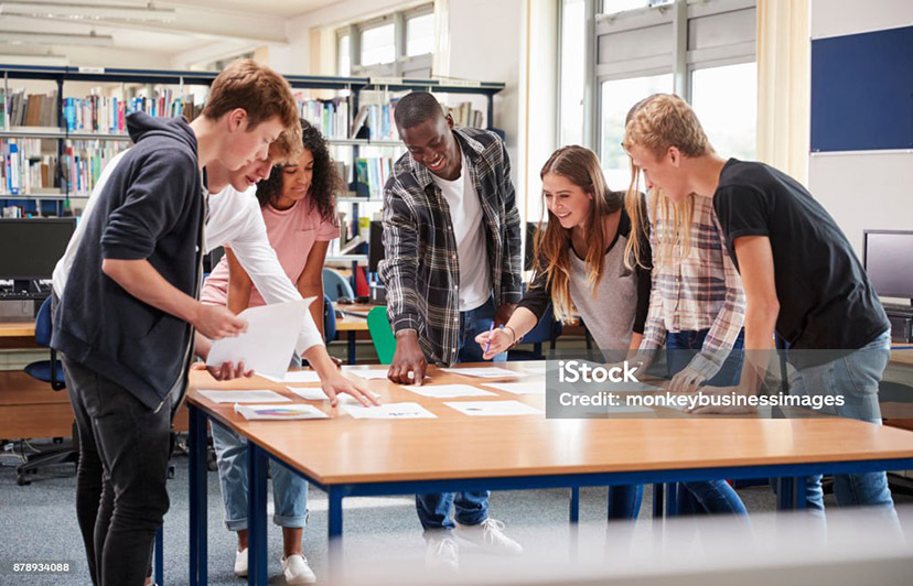 Group Of College Students Collaborating On Project In Library
